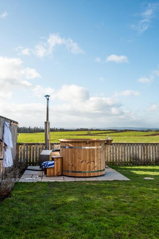 a hot tub in a yard next to a fence at Border View Cottage in Duddo