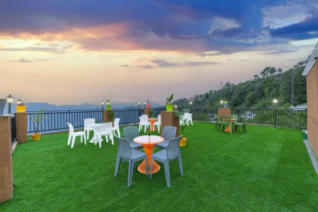 a balcony with a table and chairs on the grass at Himalayan Mist Retreat By Cloud Berry stays kasauli in Dharampur