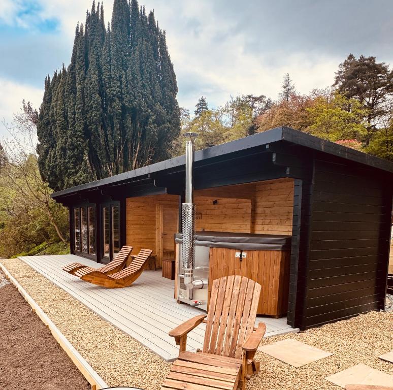 a cabin with two chairs and a grill on a deck at Lochwood House & The Wild Spa in Lochgoilhead
