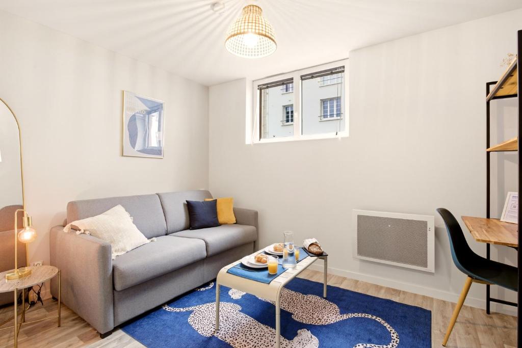 a living room with a couch and a table at Studio L'Indigo - F1 design, hypercentre - CAEN in Caen