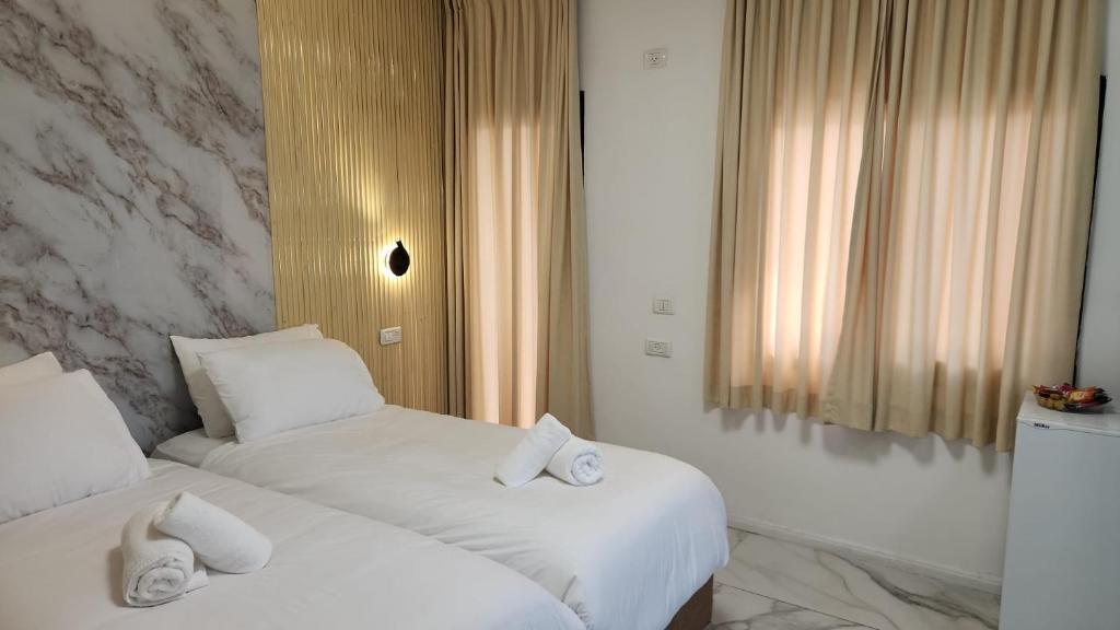 two beds in a hotel room with white sheets at אחוזת מונפלייר in Tiberias