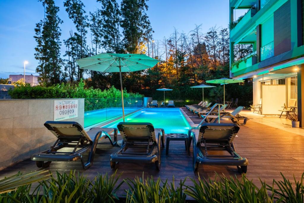 a group of chairs and umbrellas next to a pool at Rooms Oasis Life in Split