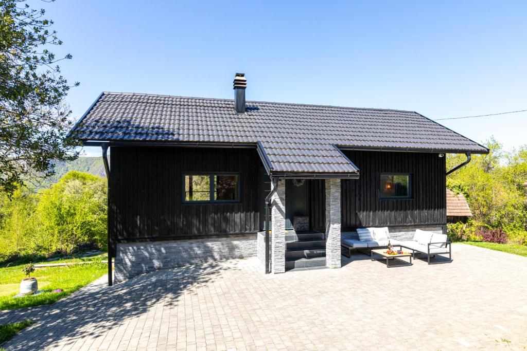 a small house with a black roof and a patio at Crossroads Hideaway in Brod na Kupi