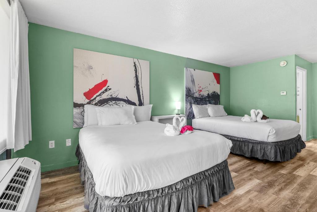 two beds in a room with green walls at Disney Studio 2 Queens & Shuttle in Kissimmee