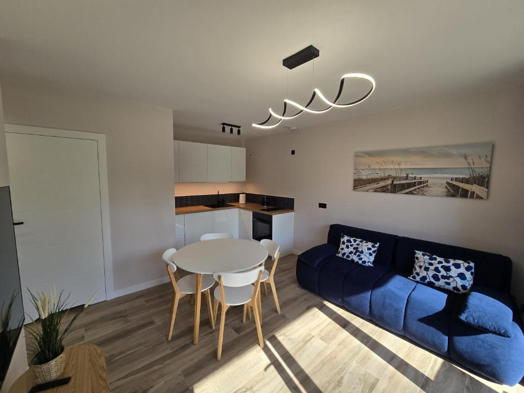a living room with a blue couch and a table at Apartamenty Miku - Łeba in Żarnowska