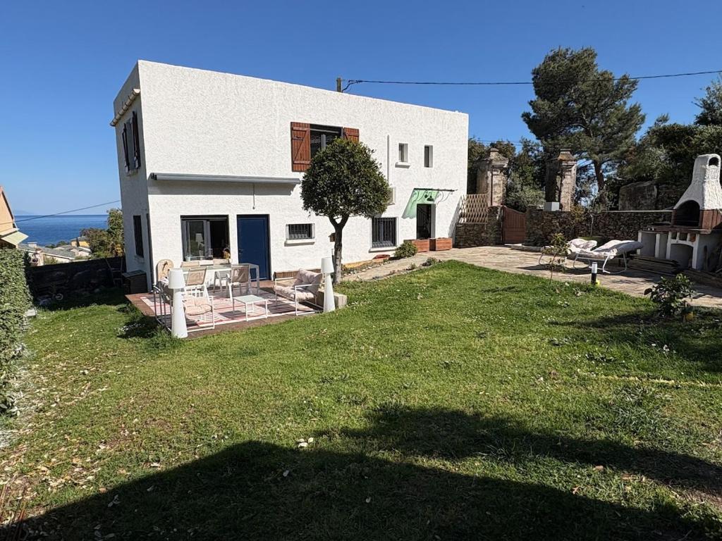a white house with a large yard with a tree at Maison Erbalunga in Brando