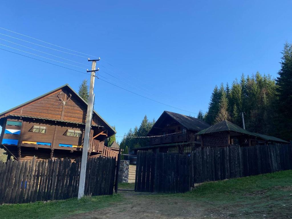 a couple of wooden houses behind a fence at Володимирська садиба in Migovo