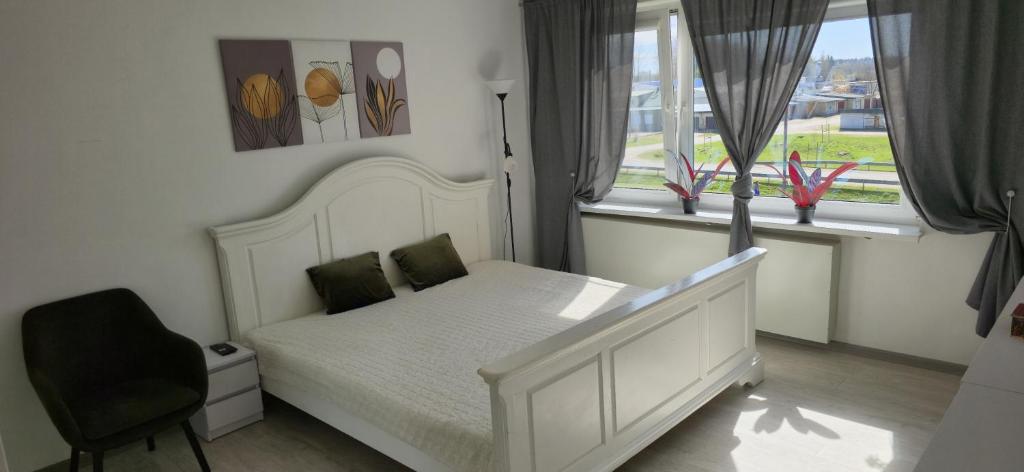 a bedroom with a white bed and two windows at Cozy Stay Širvintos in Širvintos