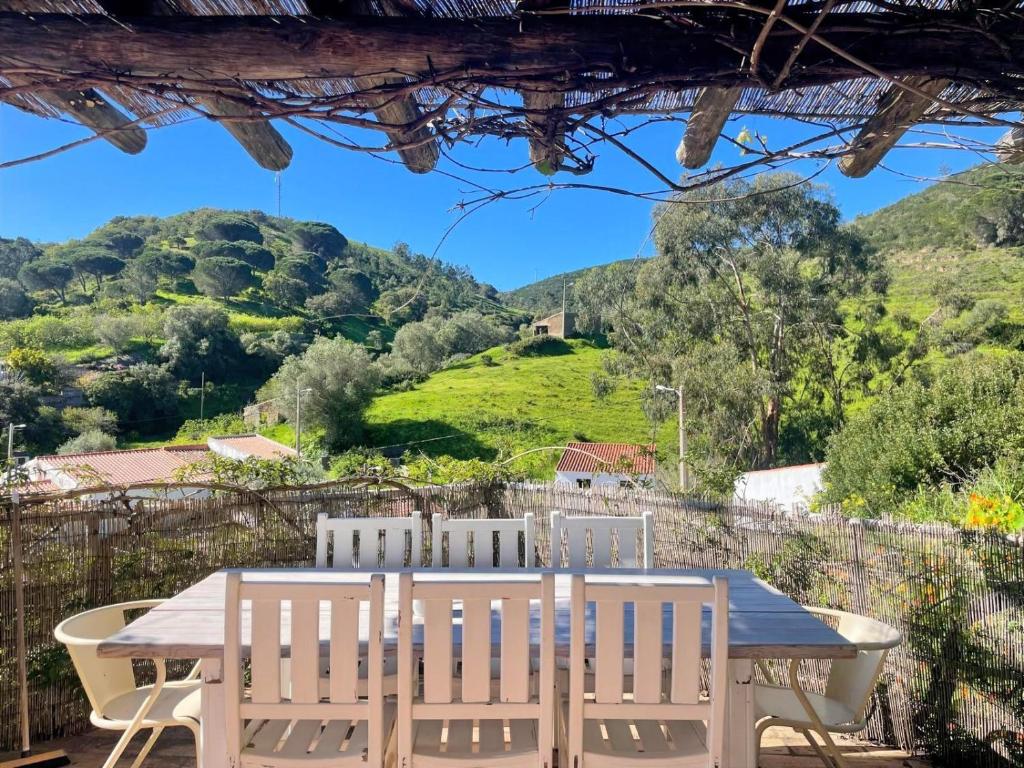 a table and chairs with a view of a hill at Tina`s House - Bordeira in Aljezur