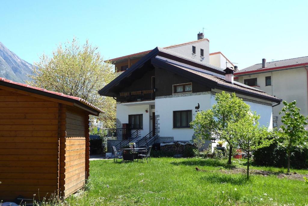 a white house with a brown roof and a yard at House Angy in Ponte nellʼAlpi