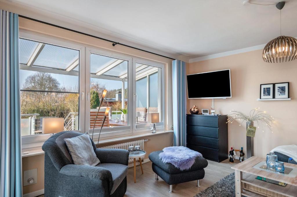 a living room with a tv and a chair and a window at Ferienhaus am See mit Boot in Mustin