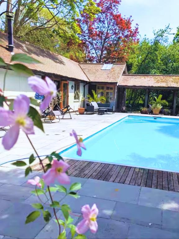 a house with a swimming pool and flowers at Rural Cottage Retreat, Near Goodwood Festival of Speed, Dog Friendly with Shared Outdoor Pool, gardens & Tennis, Free Parking! Chichester Holiday Properties in North Mundham