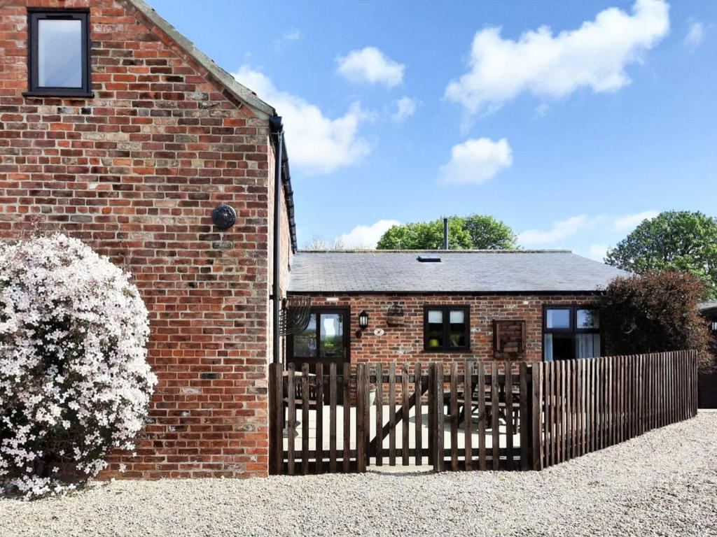 a brick house with a wooden fence in front of it at Plum Cottage in Anderby