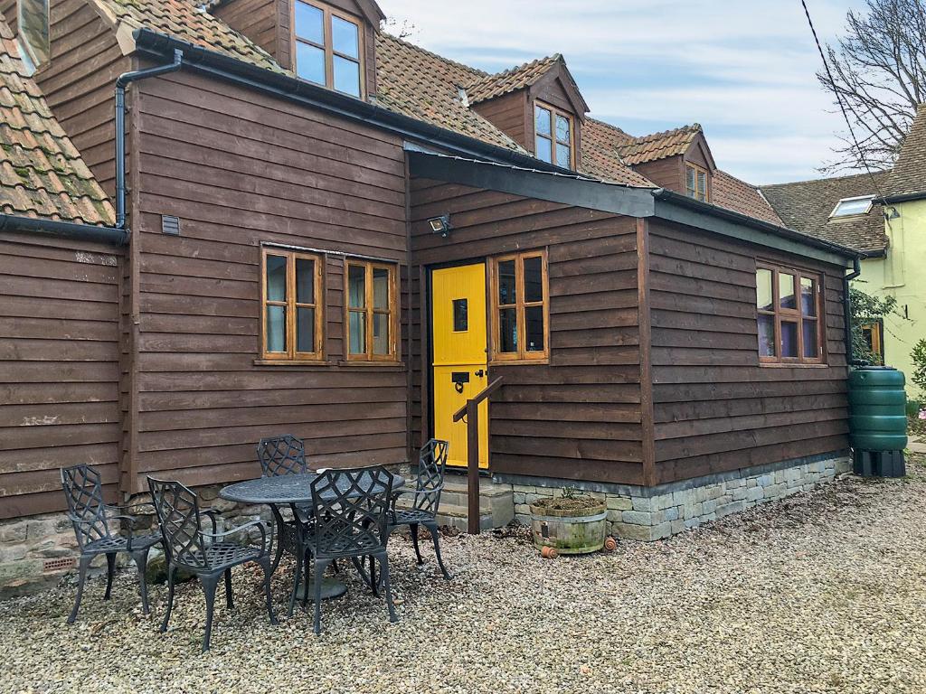 a house with a yellow door and a table and chairs at Stocks Tree Cottage in Preston Wynne