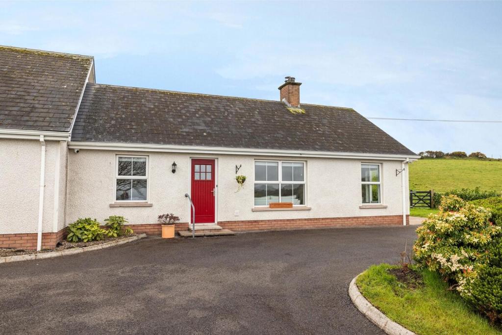 a white house with a red door and a driveway at Coolbuck Cottage in Lisbellaw