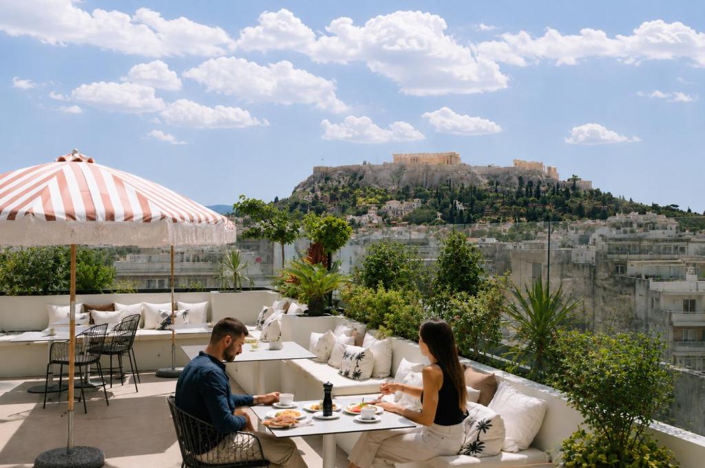 a man and woman sitting at a table on a roof at Apollo Palm Hotel in Athens