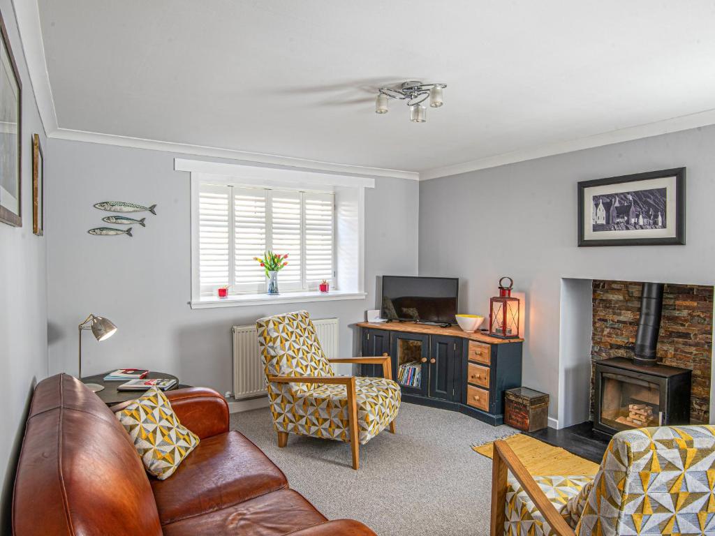 a living room with a couch and chairs and a television at Three Creeks Cottage in Portknockie