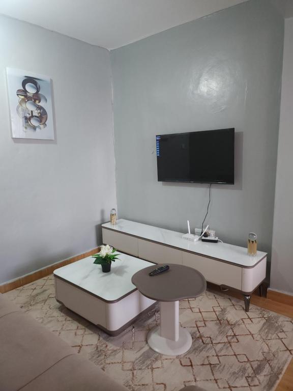 a living room with a table and a tv on the wall at Zariah Homes 1 in Kakamega