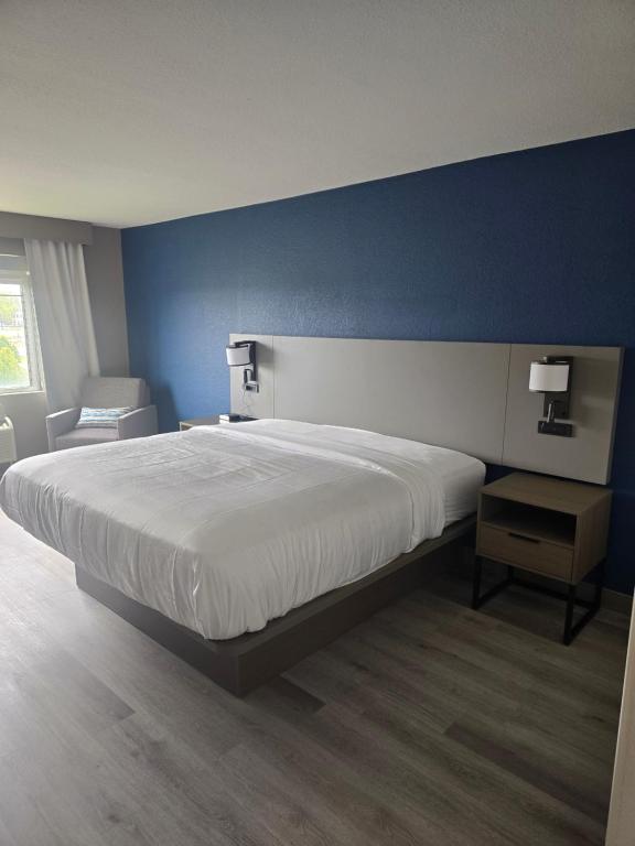 a bedroom with a large bed and a blue wall at Rodeway Inn in Portage