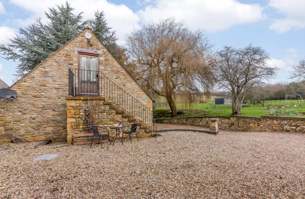a stone house with a balcony and a table and chairs at The Nest at Robins Roost in Little Rissington