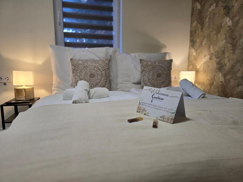 a white bed with a sign on top of it at Centrum Apartman in Nagykálló