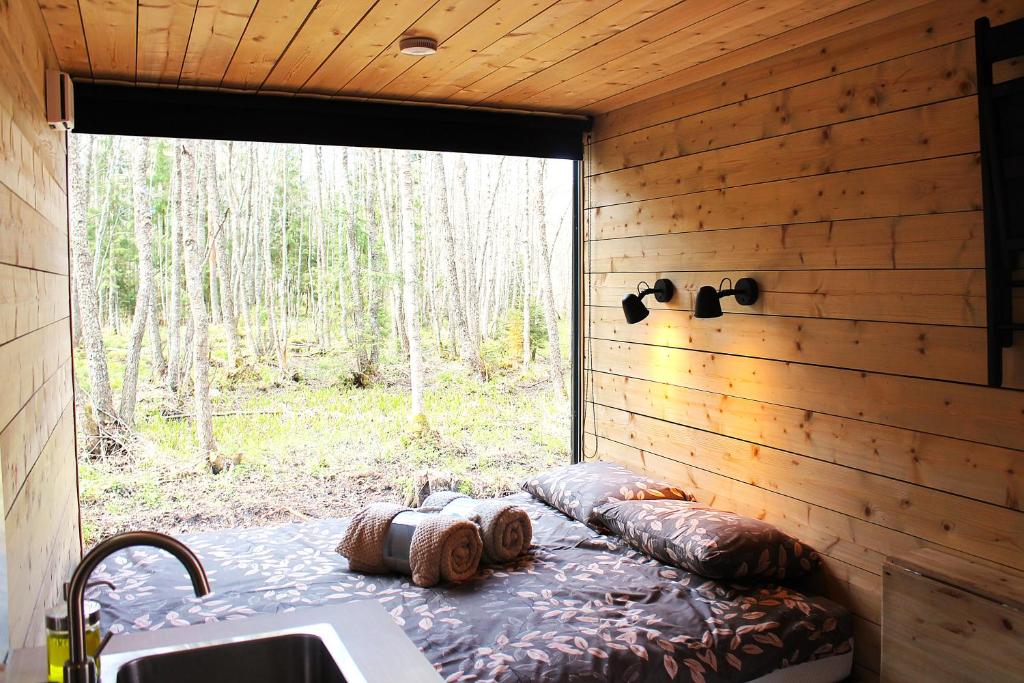a bed in the corner of a room with a window at PRIVAATNE Metsamajake SAUNAGA "KOHIN" in Sigula