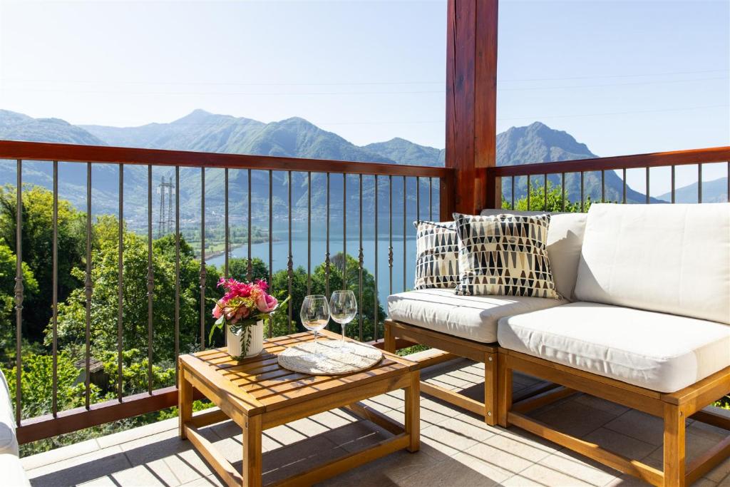 a balcony with a couch and a table with wine glasses at IseoLakeRental - Casa Lani in Costa Volpino