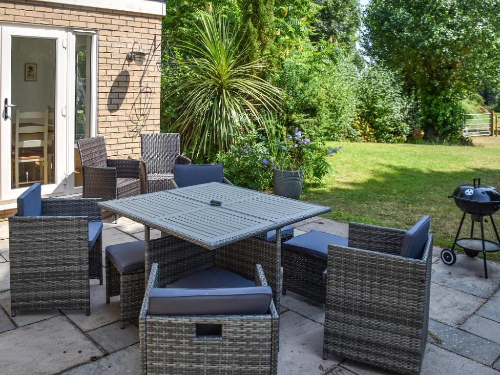 a patio with a table and chairs and a grill at Riverside in Wimblington