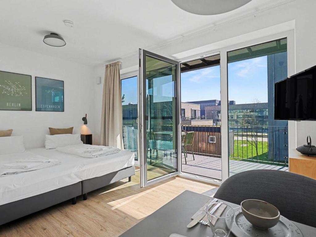 a white bedroom with a bed and a balcony at Apartment Seebrise by Interhome in Lembruch