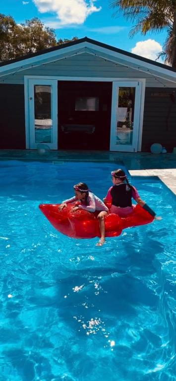 two people in a red kayak in a swimming pool at Woy Woy Staycation - Heated Pool & Hot Tub & BBQ & Pizza Oven & Arcade Game & Pool Table in Woy Woy