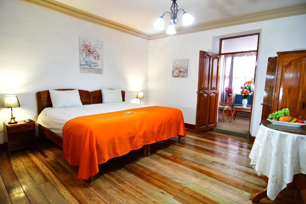 a bedroom with a bed with an orange blanket at Centenario Inn in Cusco