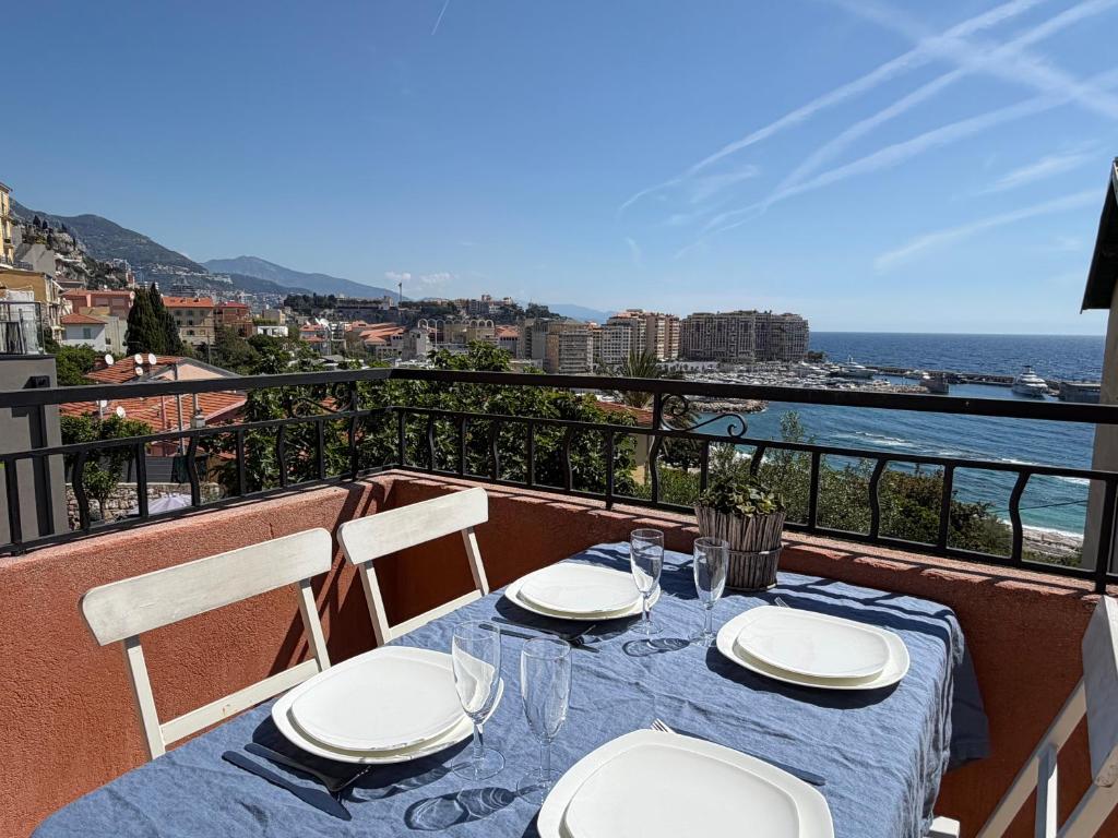 a table with plates and glasses on a balcony with the ocean at Spacieux triplex avec vue mer, proche de Monaco, 54 m2 in Cap d'Ail