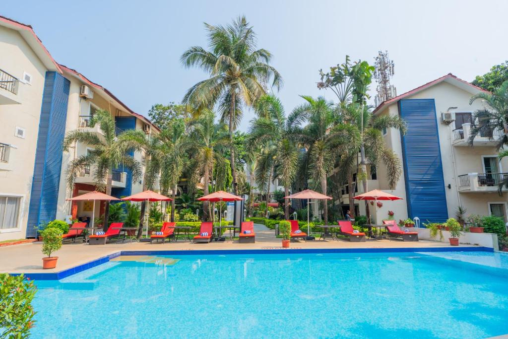 a pool at a resort with chairs and umbrellas at Kyriad Prestige Goa by Mastiff in Calangute