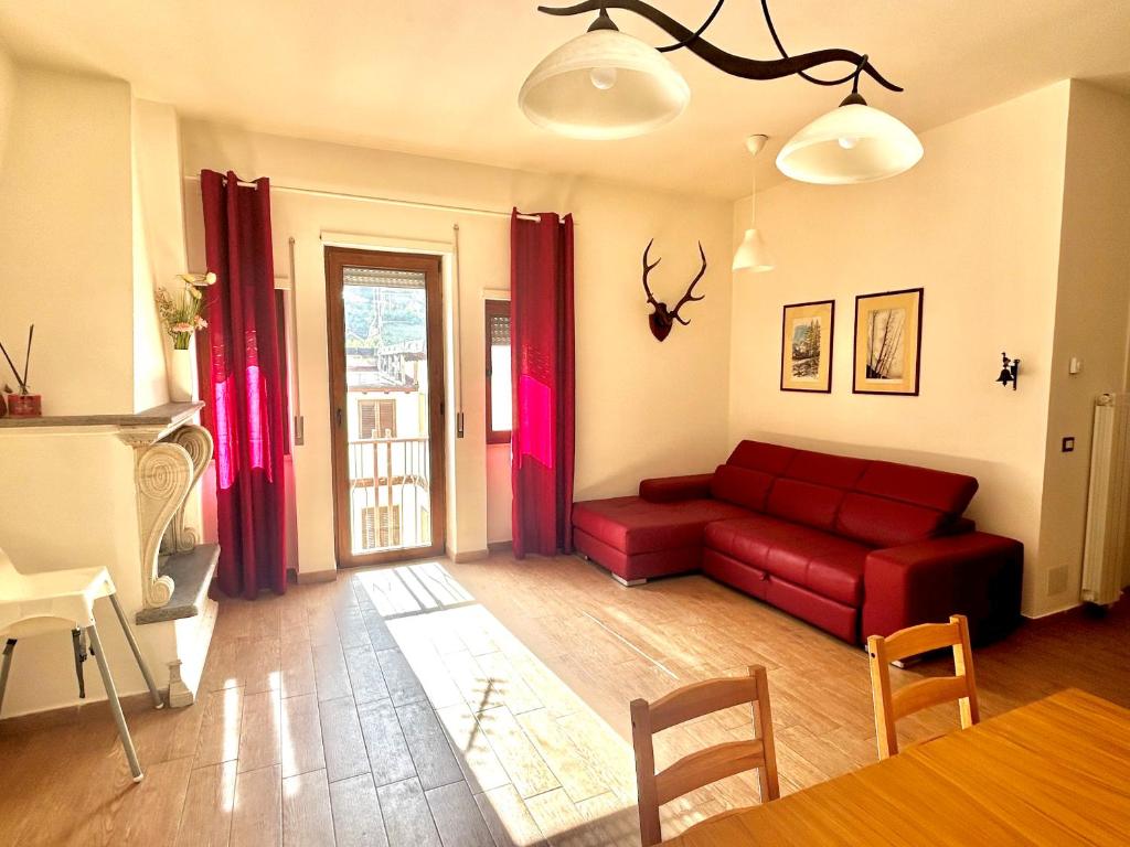 a living room with a red couch and a table at Appartamento Cuore D’Abruzzo in Scanno