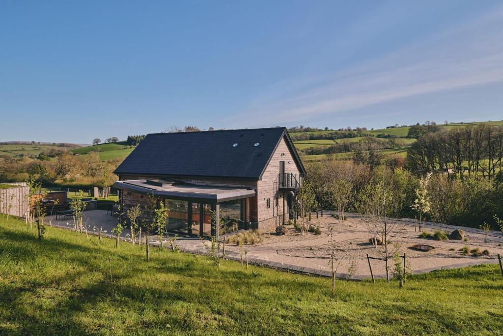 ein Haus mit schwarzem Dach auf einem Feld in der Unterkunft Grain Loft in Trefeglwys