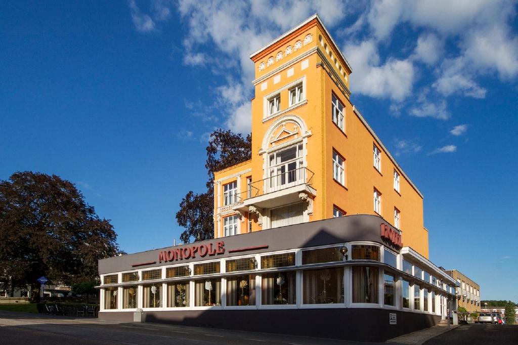 a tall yellow building with a sign on it at Grand Hotel Monopole in Valkenburg