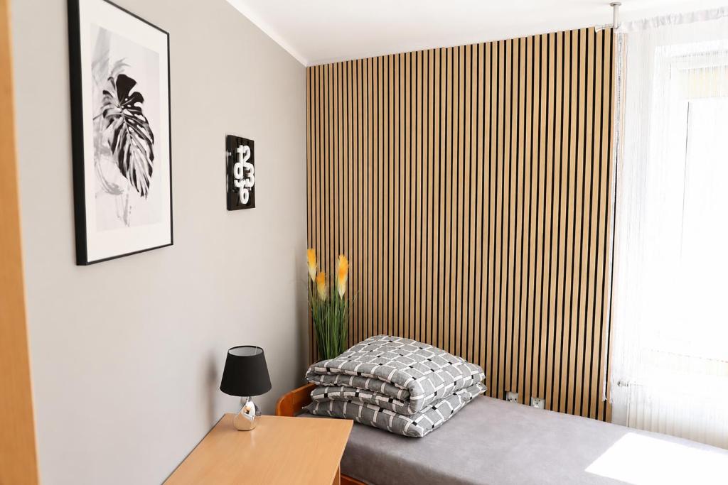 a bedroom with a bed and a wooden wall at Kwatery Fado in Częstochowa
