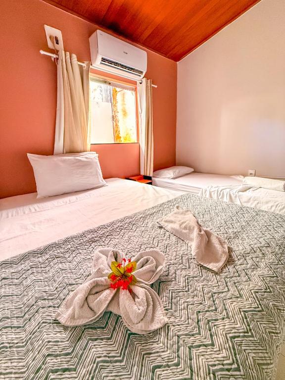 a bedroom with a bed with a flower on it at Pousada Timbalada in Morro de São Paulo