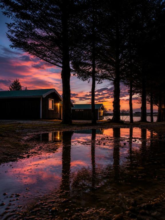 a sunset with a reflection of a house in a puddle at Arhus Cottage and Camping in Hella