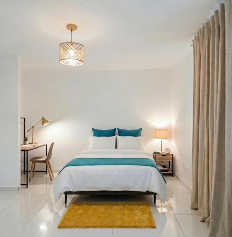 a white bedroom with a bed and a desk at Location meublee Kourou pour 5 personnes plus 1 bebe in Kourou