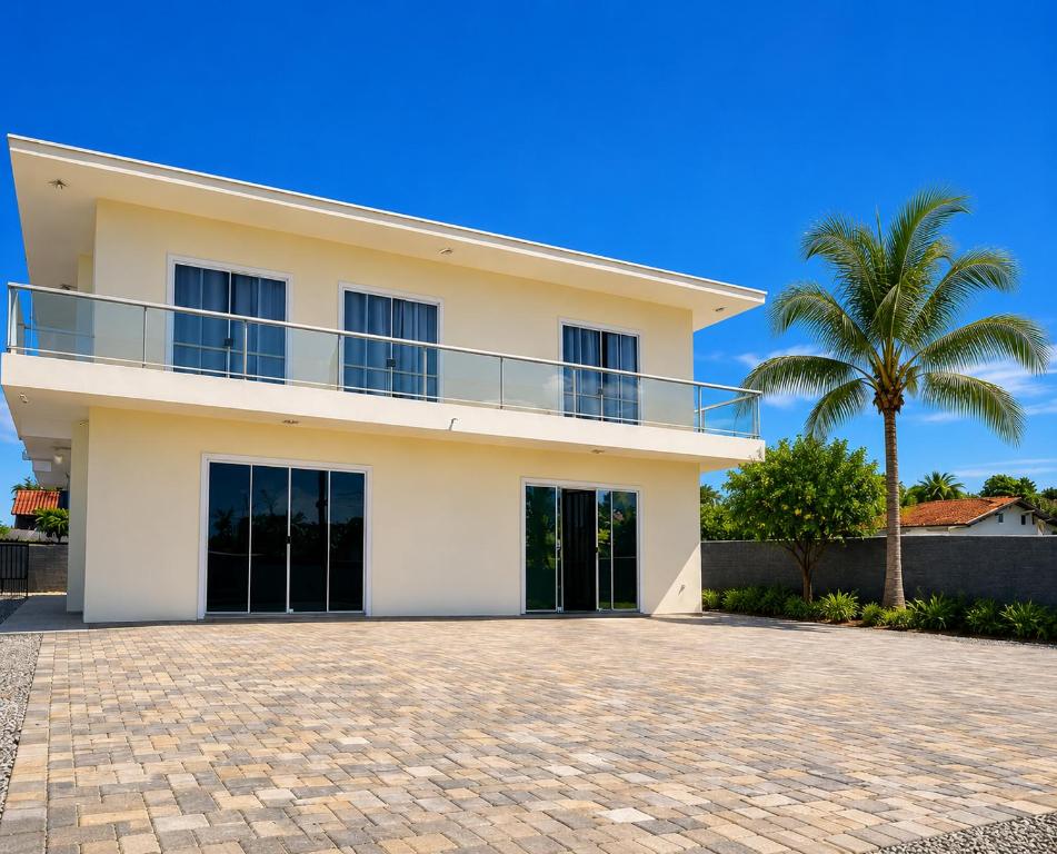 a white house with a palm tree in front of it at Pousada Central Araquari in Araquari