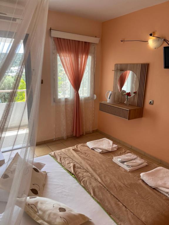 a bedroom with a bed and a mirror and a window at Isidora Hotel in Agia Marina Aegina