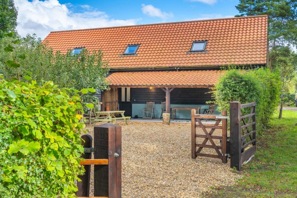 a house with an orange roof and a fence at The Roost in Wendling