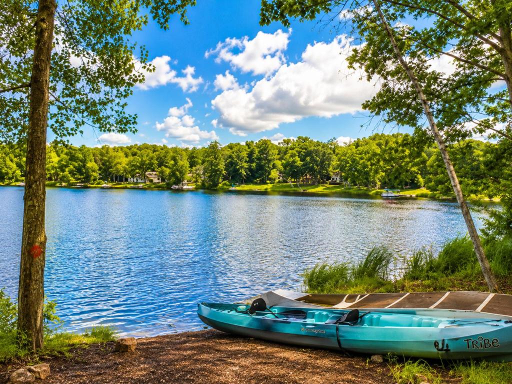 a blue boat parked on the shore of a lake at Arrowhead Lakefront Chalet Private Lake Access in Pocono Lake