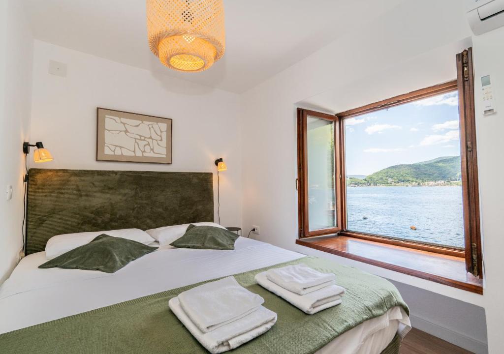a bedroom with a bed with a large window at Seafront Stone House Maxim in Tivat