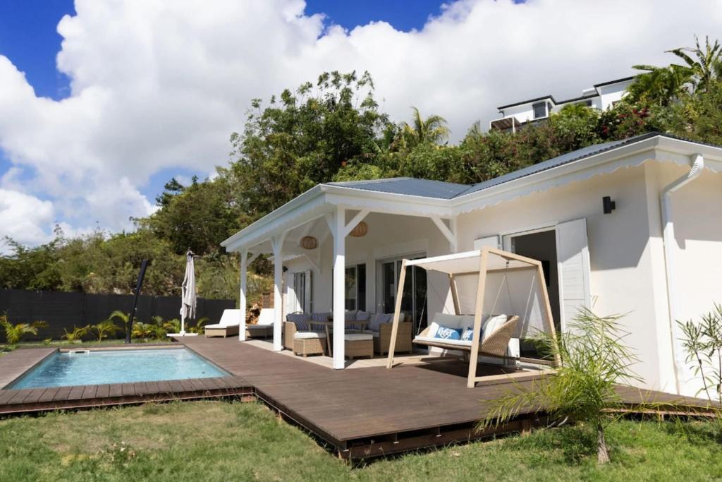 a white house with a deck and a swimming pool at Villa Duna 2 Bedrooms Pool & Tropical Atmosphere in Sainte-Anne