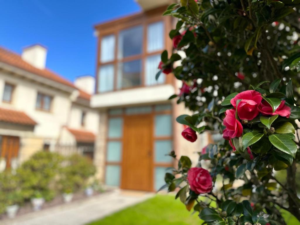 a house with a bush with roses in front of it at "LAS CAMELIAS SOMO" un lugar para desconectar!! Vistas al MAR!! in Somo