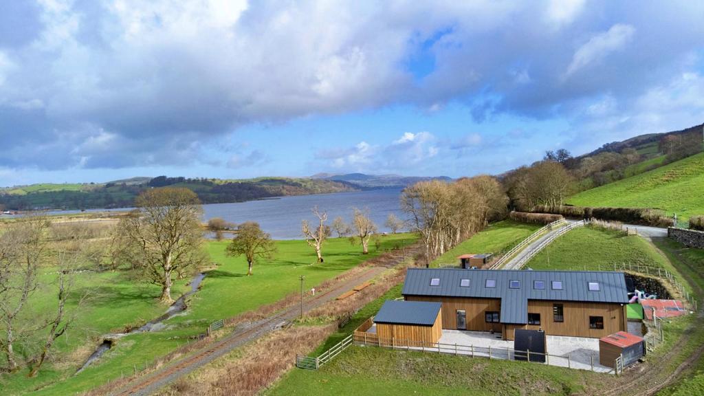 an aerial view of a house in a field next to a lake at Finest Retreats - Cae Rhug in Llanuwchllyn