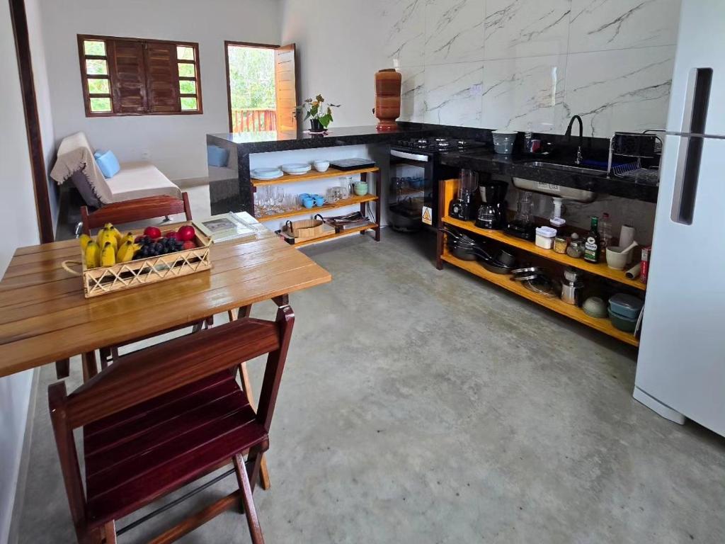 a kitchen with a table with a bowl of fruit on it at Chalés Refúgio da Sil in Cavalcante