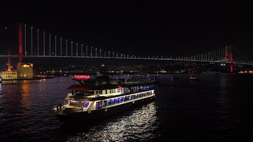 a boat in the water near a bridge at night at Bosphorus Tour Organization in Istanbul